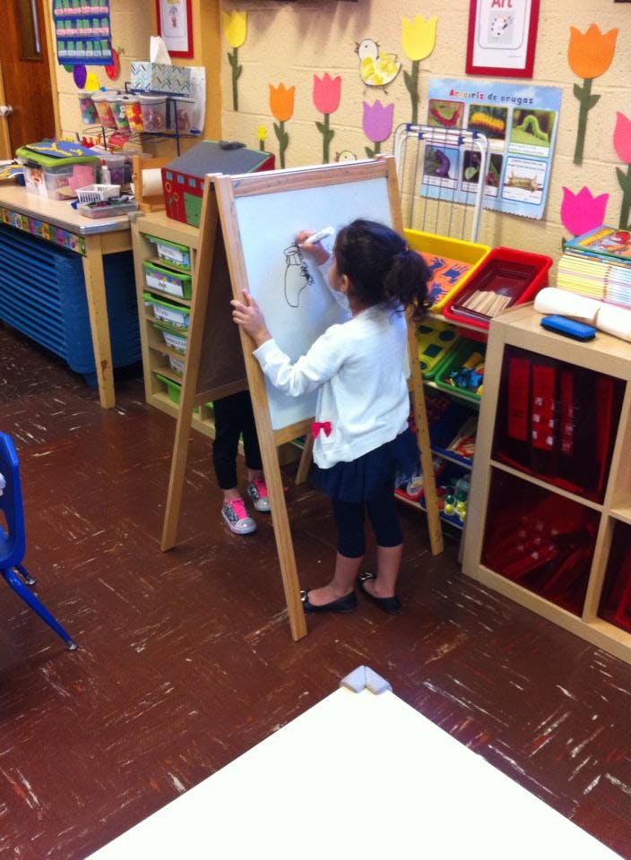 Child drawing on an easel in a classroom