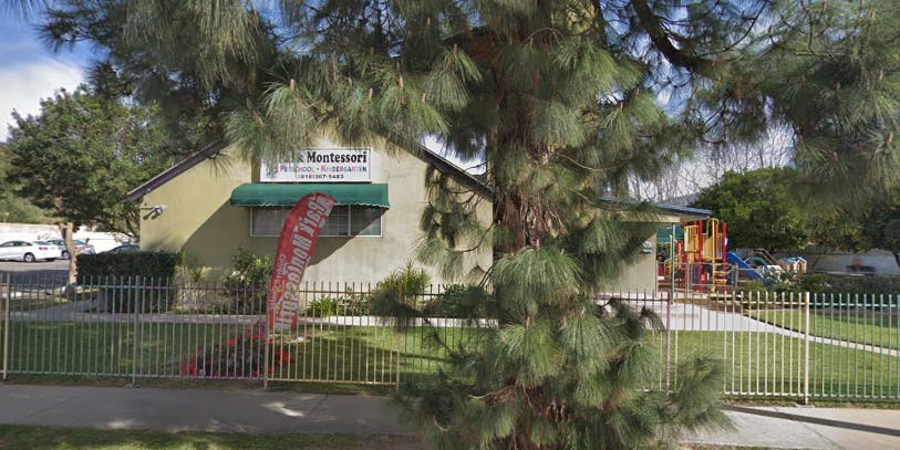 Building with green awning and red banner, playground behind a fence
