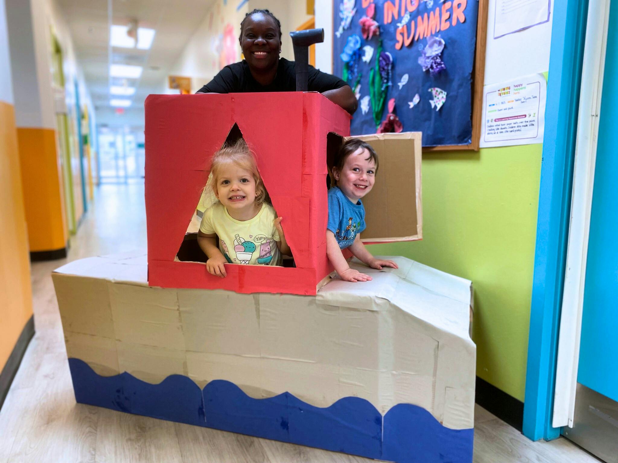 Adult and two children playing in a cardboard boat