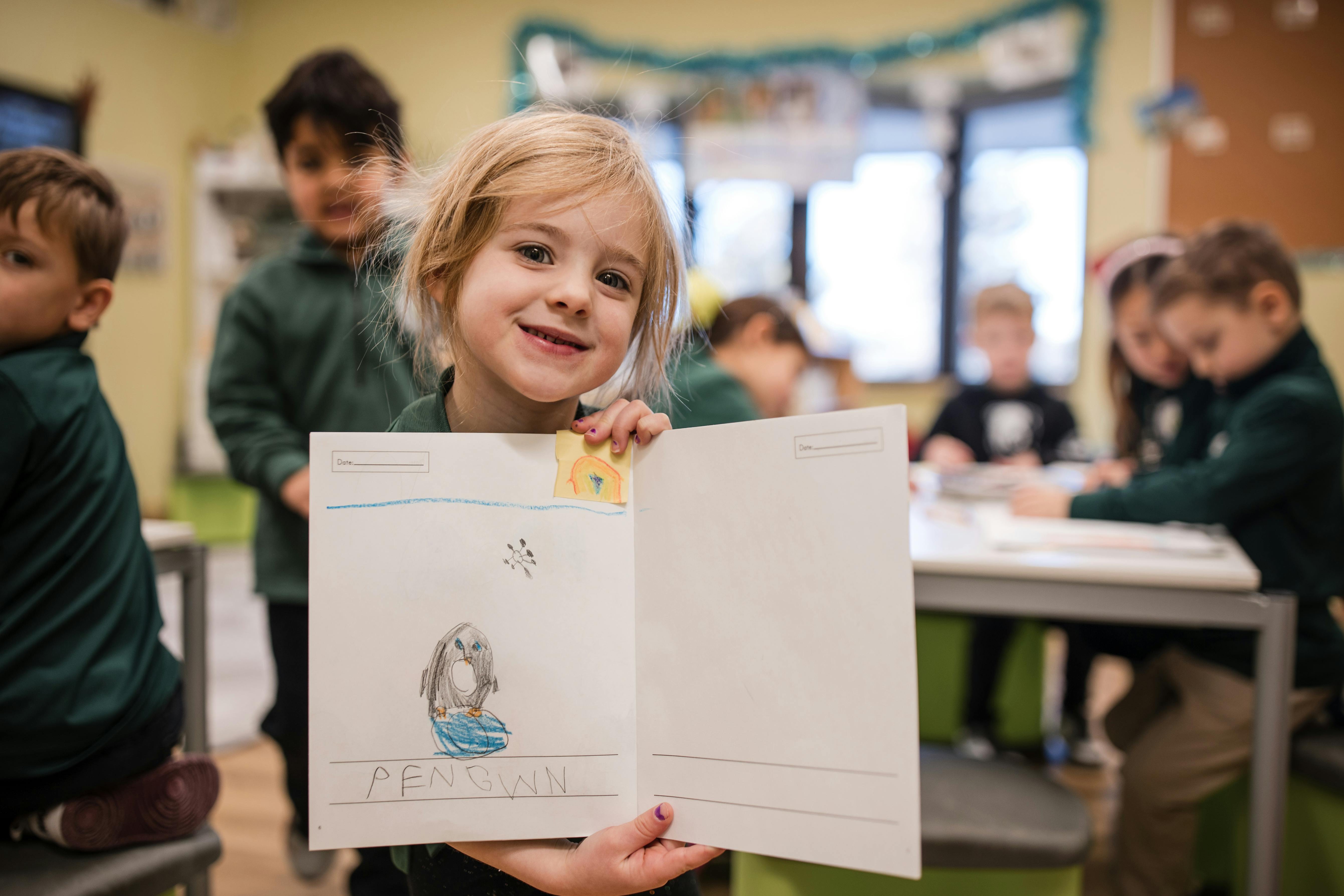 Child holding up a drawing in a classroom