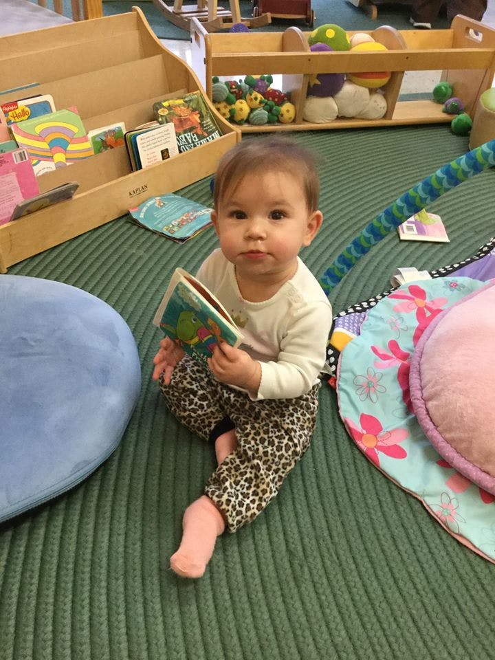 Child sitting on floor holding a book