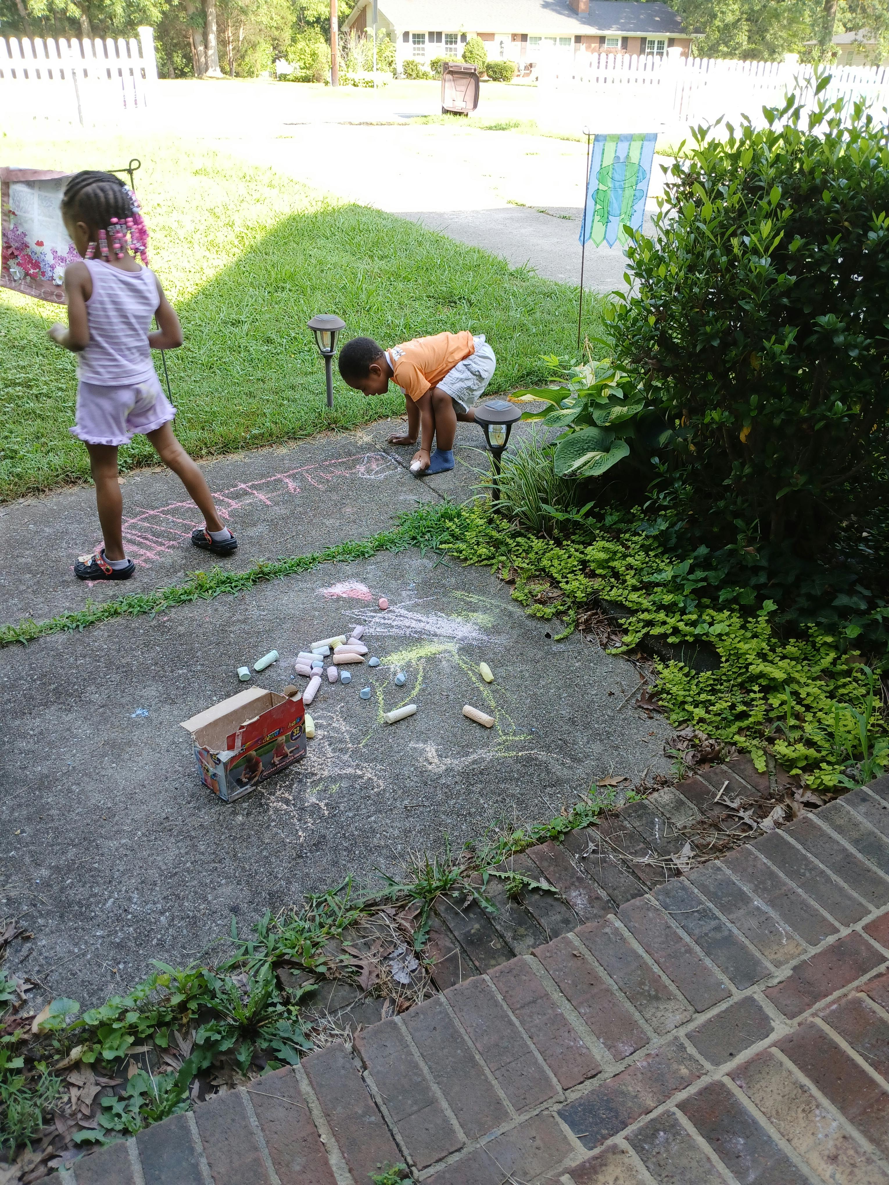 Two children drawing with chalk on a sidewalk