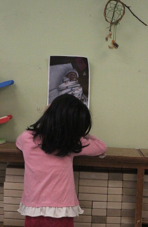Child looking at a photo of a swaddled infant