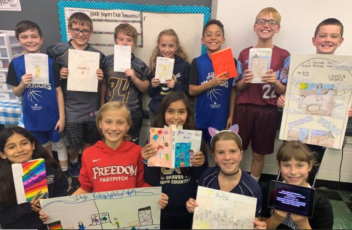 Group of children holding up various drawings and books