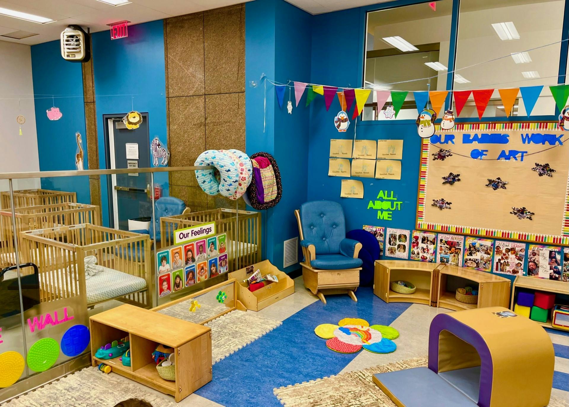 cribs in a childcare classroom with a blue rocking chair and colorful decorations
