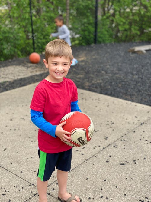 Child in red shirt holding a soccer ball