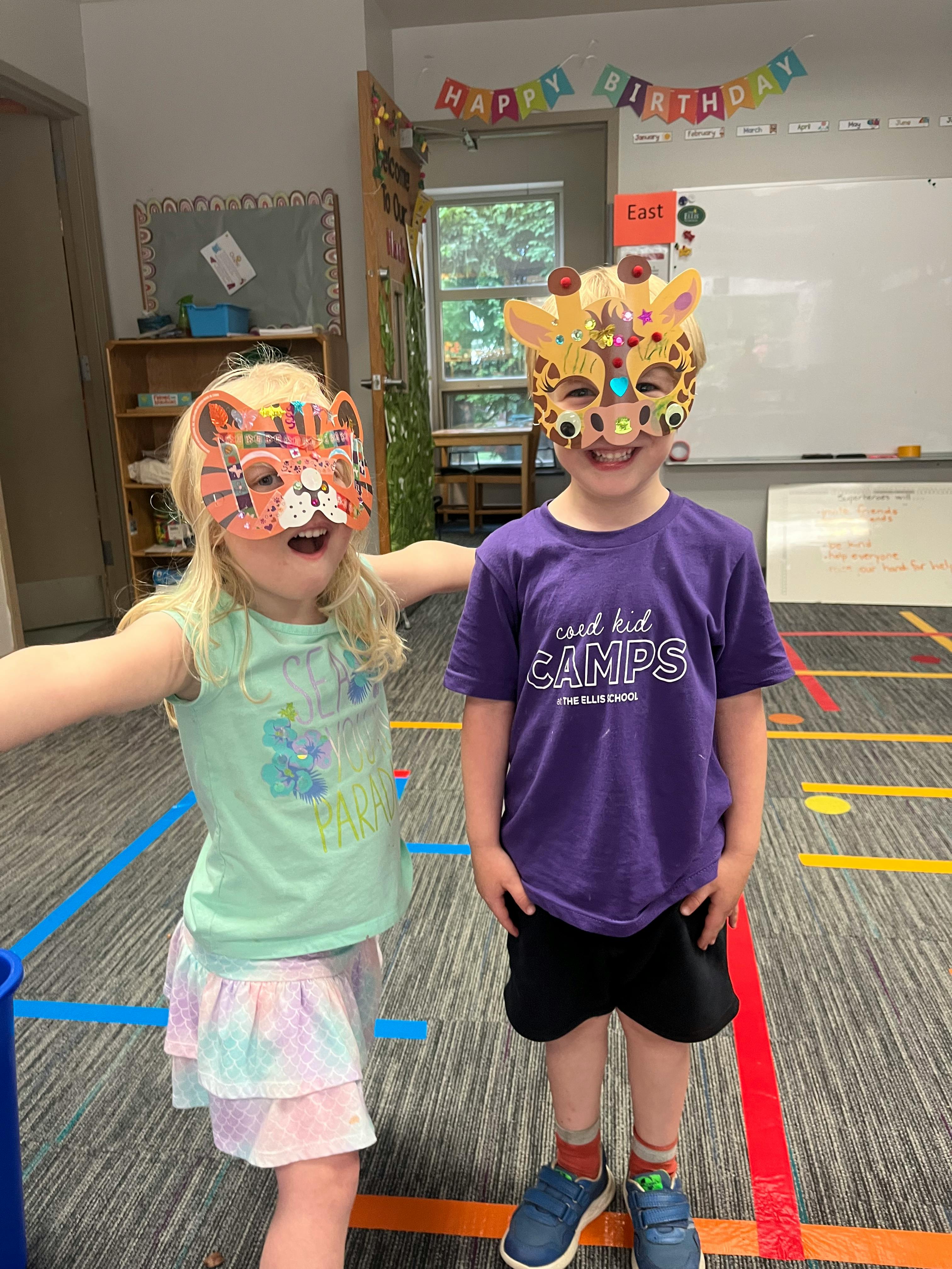 Two children wearing animal masks in a classroom