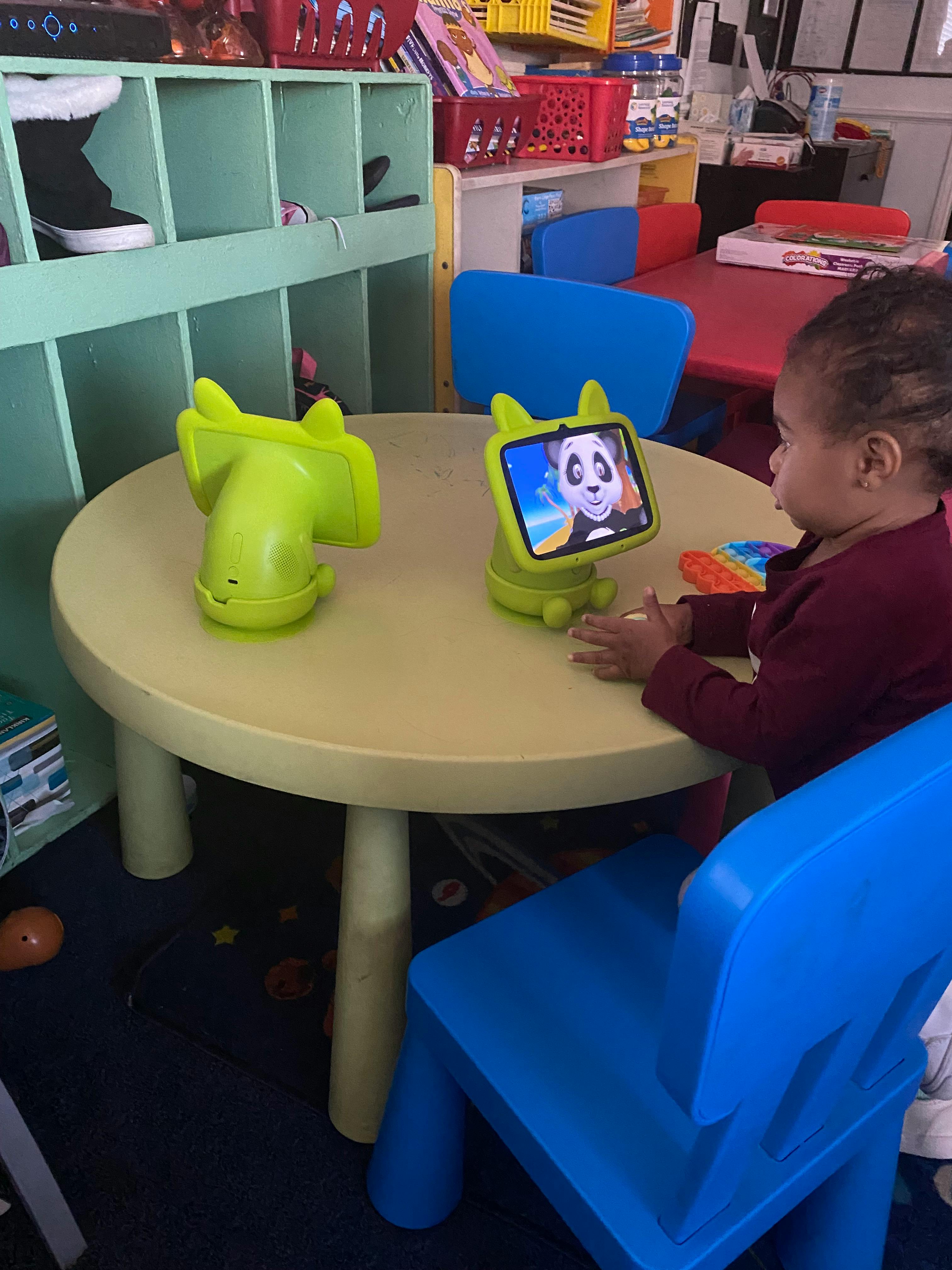 Child sitting at a table using a small interactive tablet