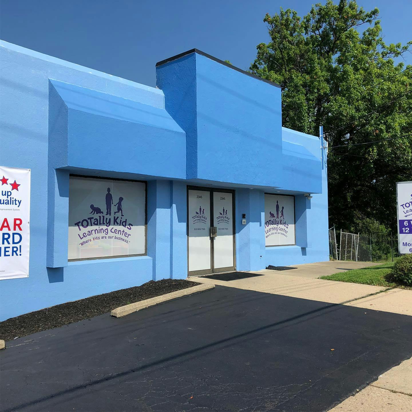 Exterior of a blue building with "Totally Kid Learning Center" on the window