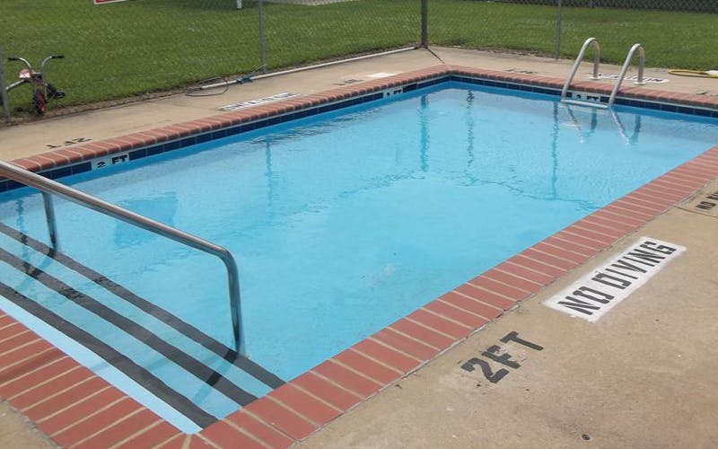 An outdoor swimming pool with blue water and red brick coping