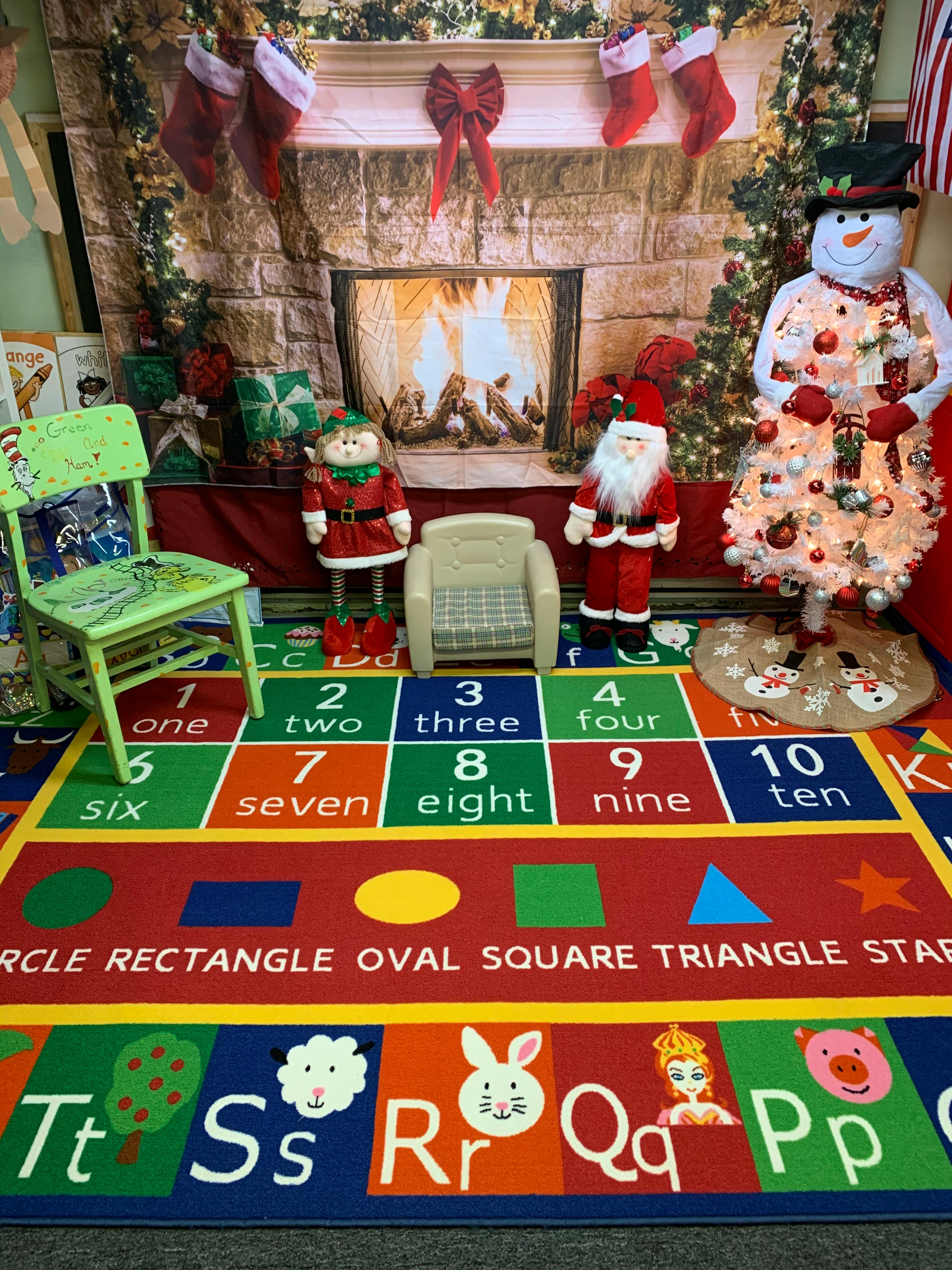 Christmas decorations with a fireplace backdrop and a colorful learning rug