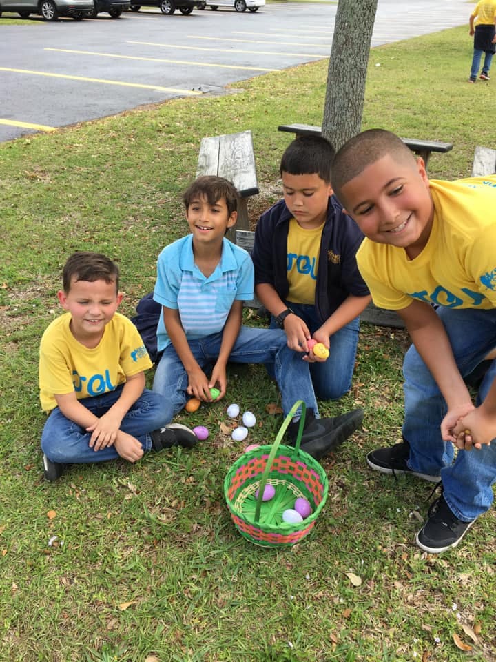 Four children on grass with Easter eggs and a basket