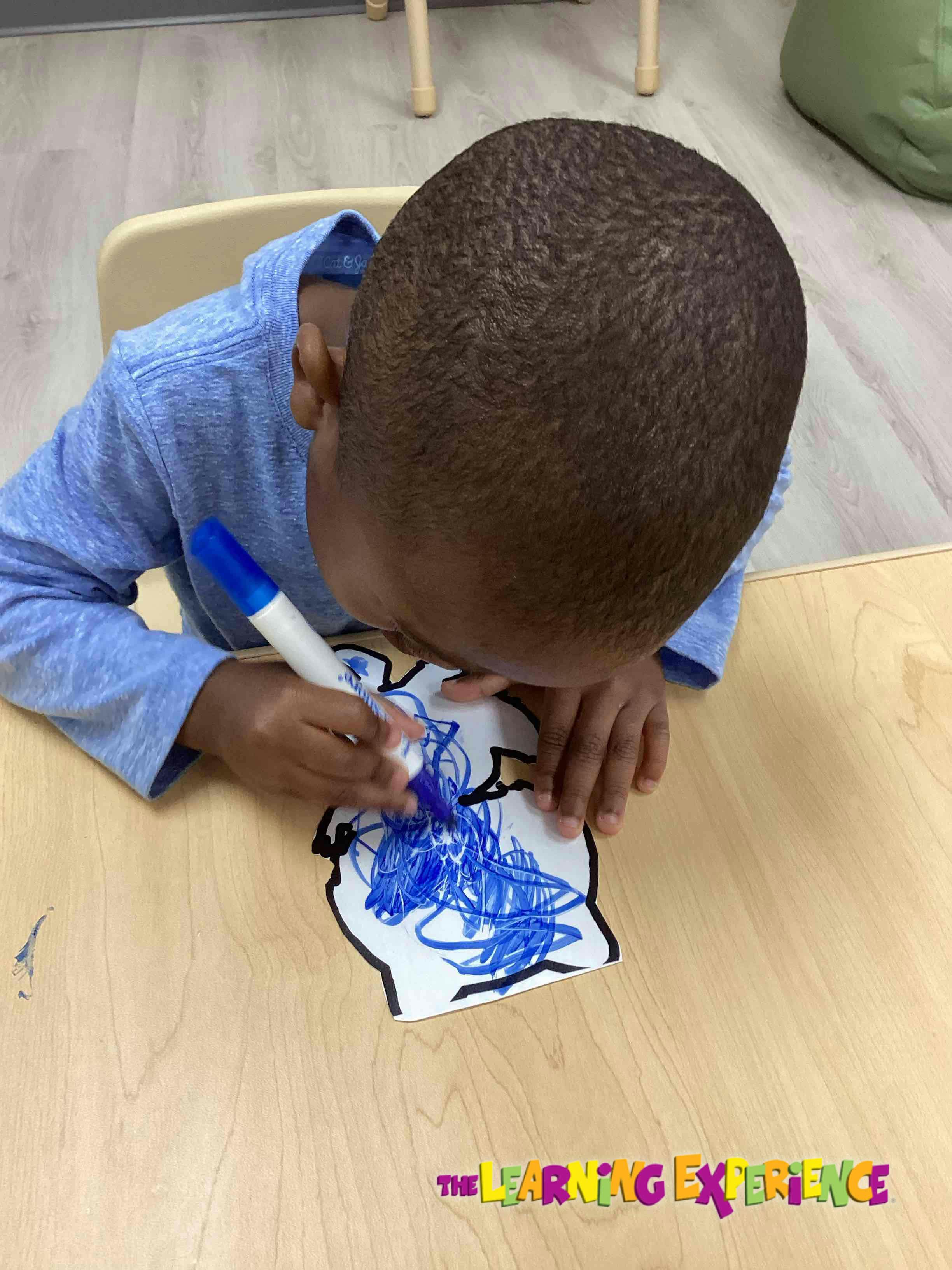 Child drawing on paper with a blue marker