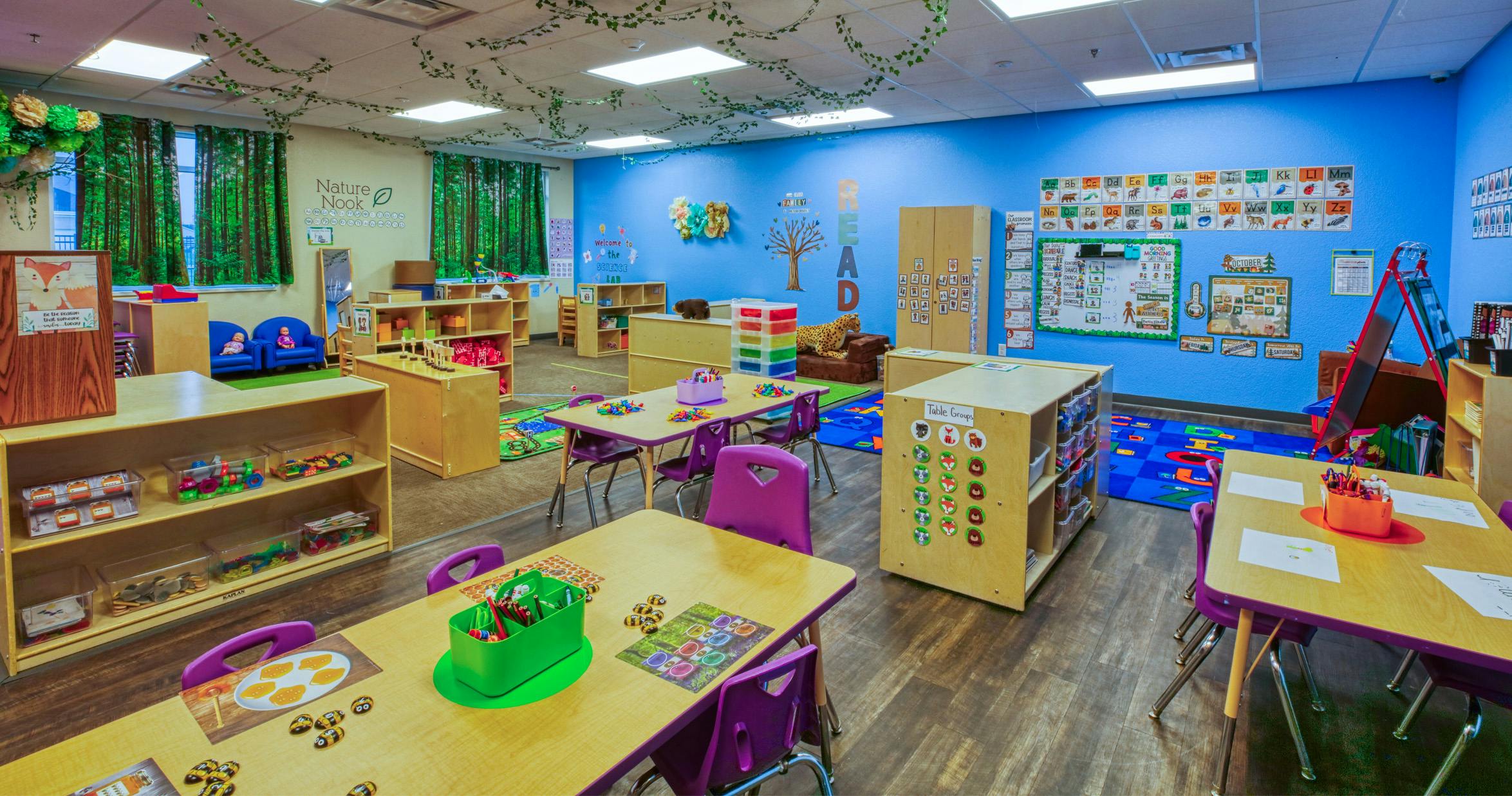 Children's classroom with blue and white walls, tables, chairs, and learning materials