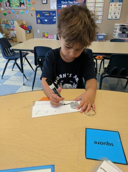 Child drawing on paper with a marker in a classroom