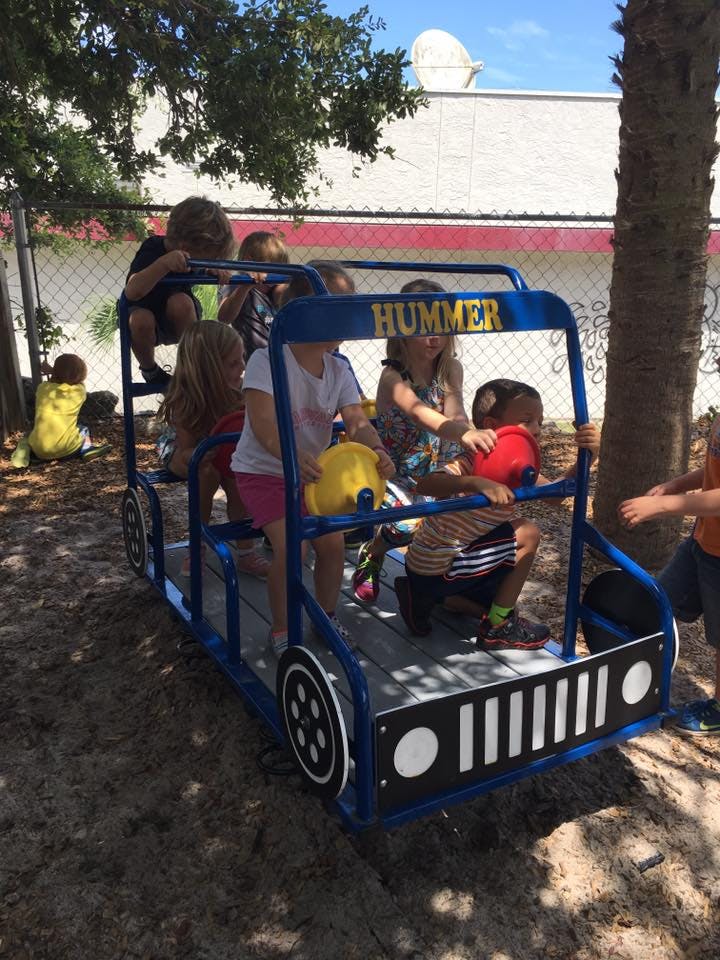 Children playing on a blue toy car with "HUMMER" written on it