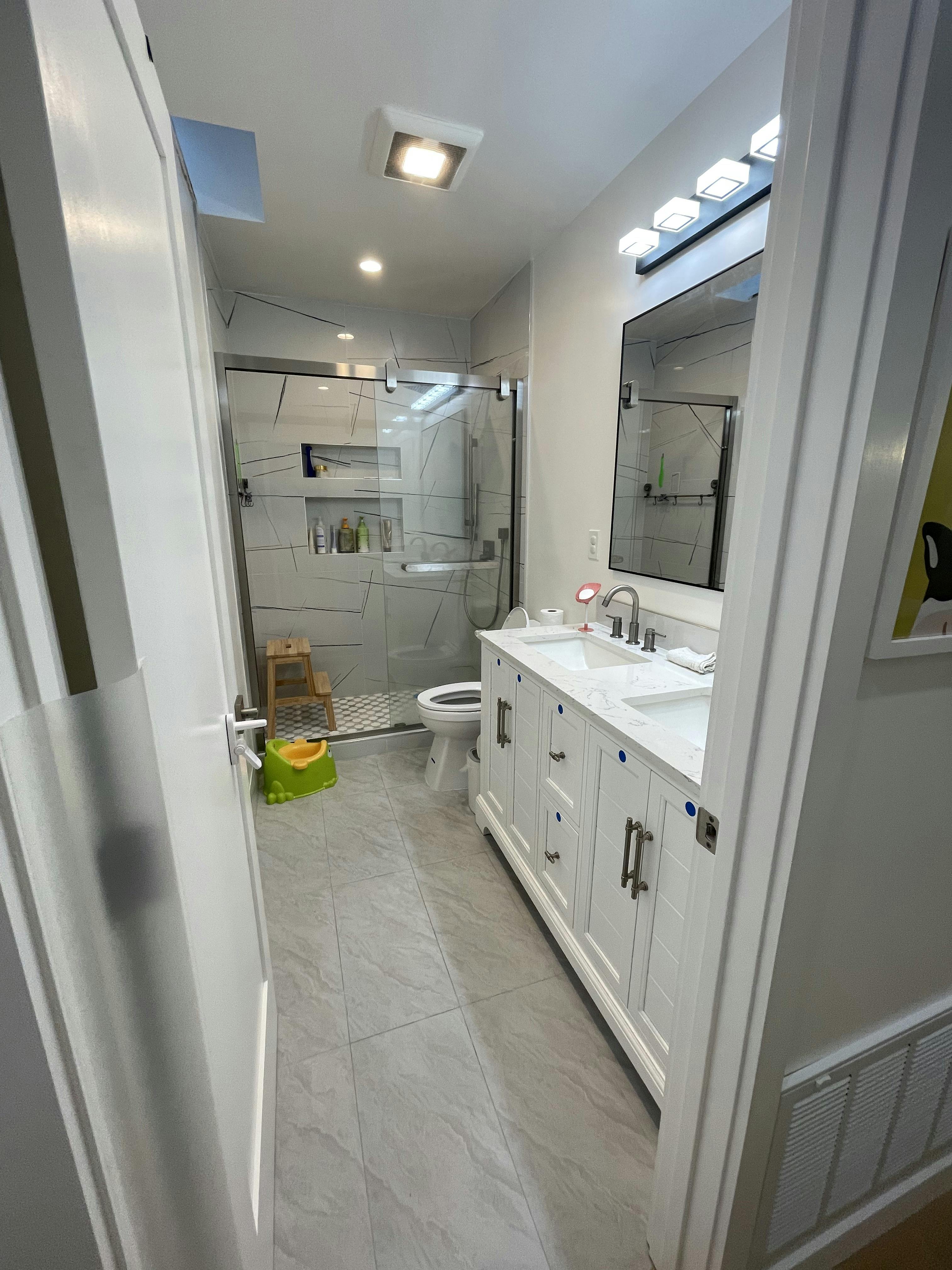 Bathroom with a double vanity, toilet, and glass-enclosed shower