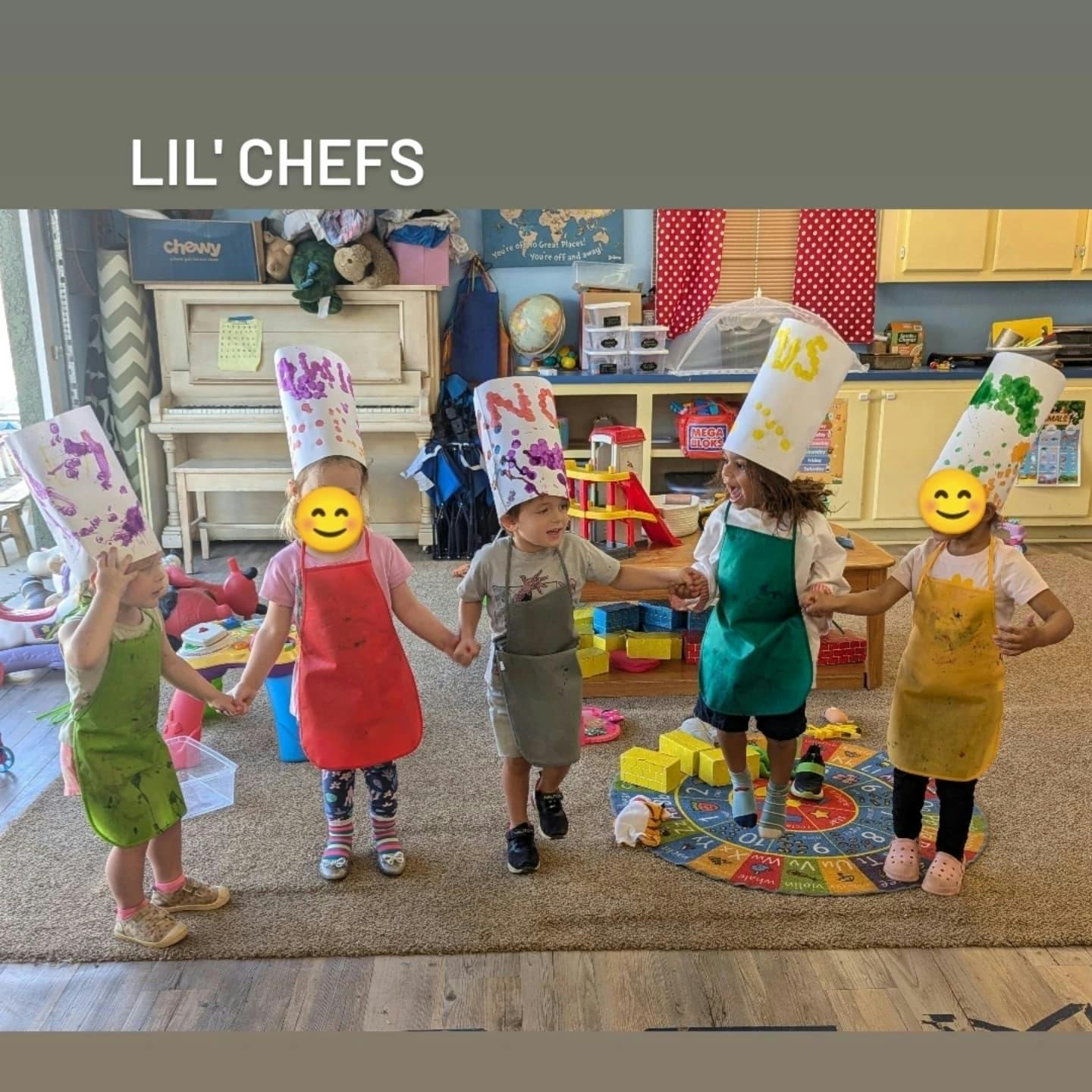 Children wearing chef hats and aprons holding hands in a classroom