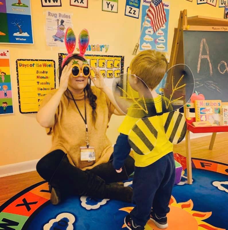 Person wearing novelty glasses and bunny ears with a child in a bee costume