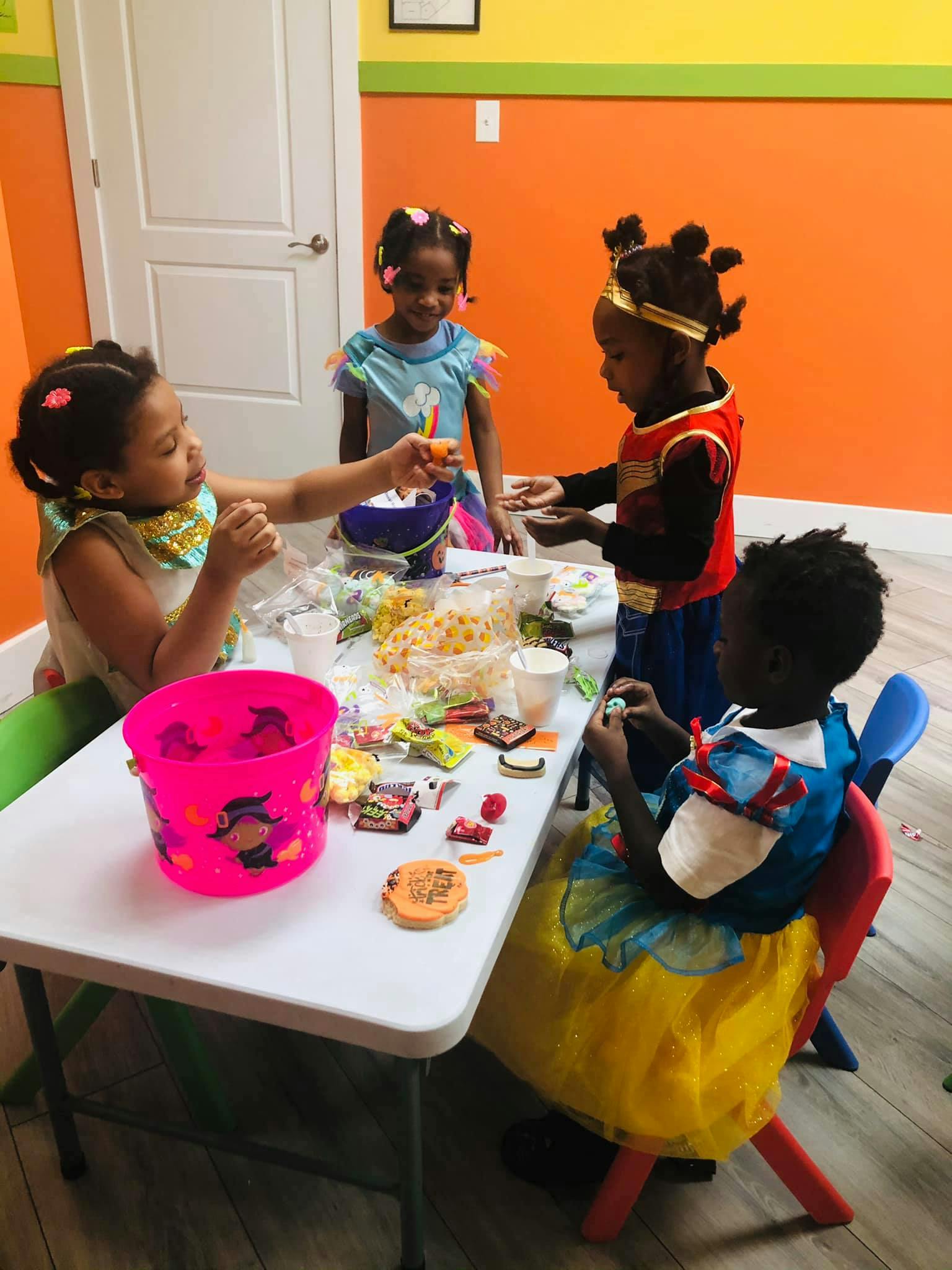 Four children at a table with snacks and craft supplies
