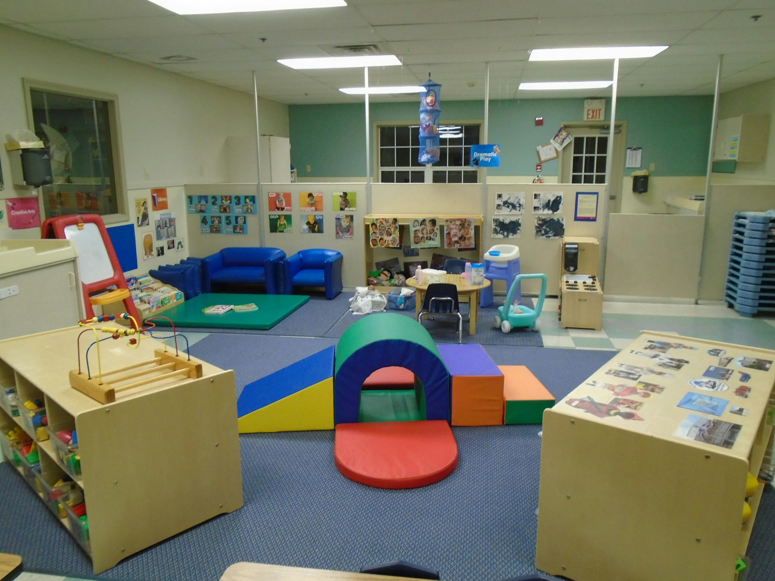 Classroom with children's play equipment, including a soft play tunnel and blue sofas