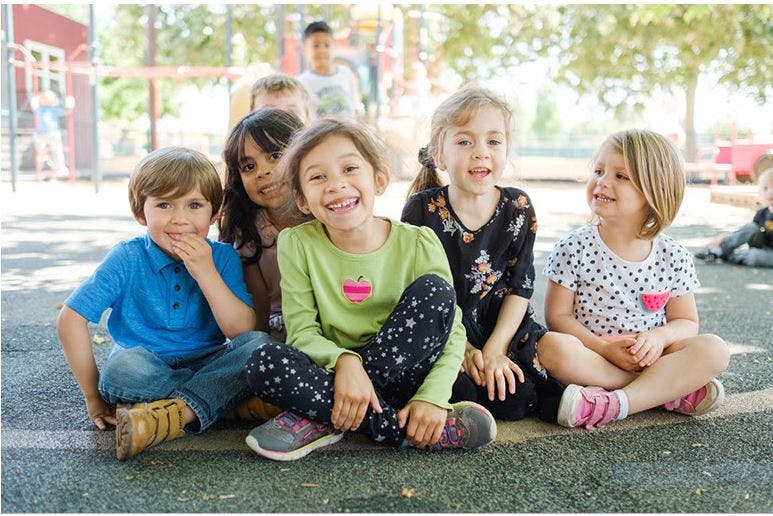 Group of children sitting on the ground outdoors