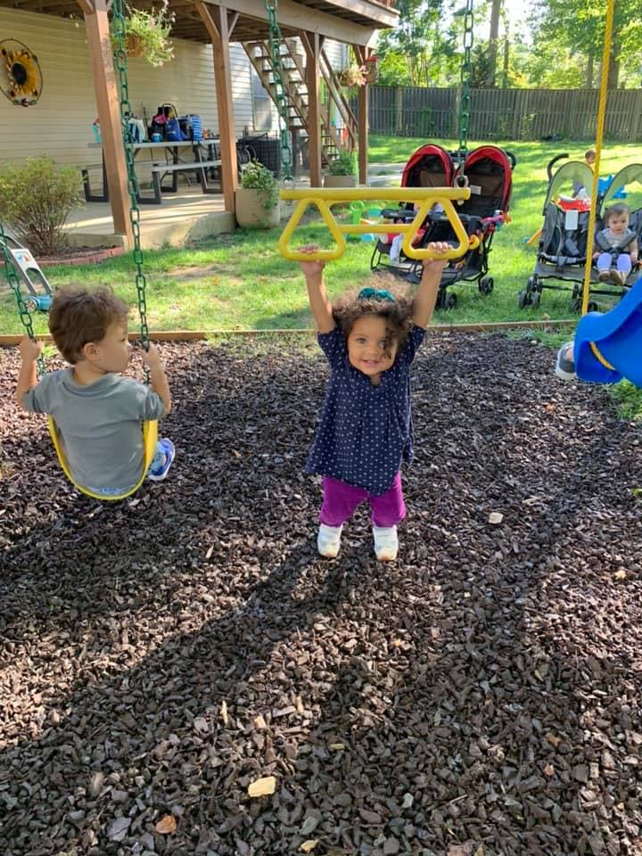 Two children playing on a swing set in a backyard