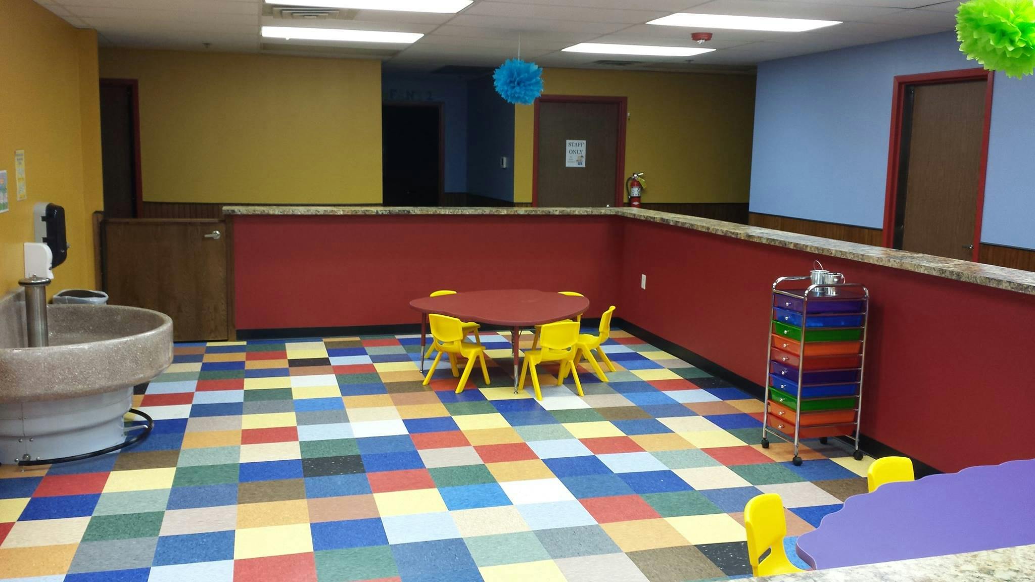 Playroom with small table and chairs, colorful floor, and water fountain