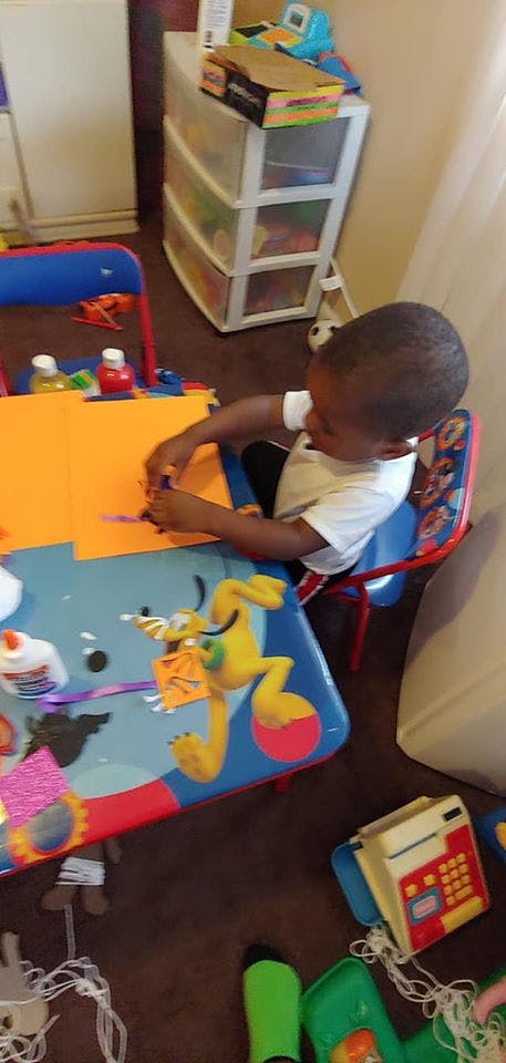 Child sitting at a table doing crafts with craft supplies