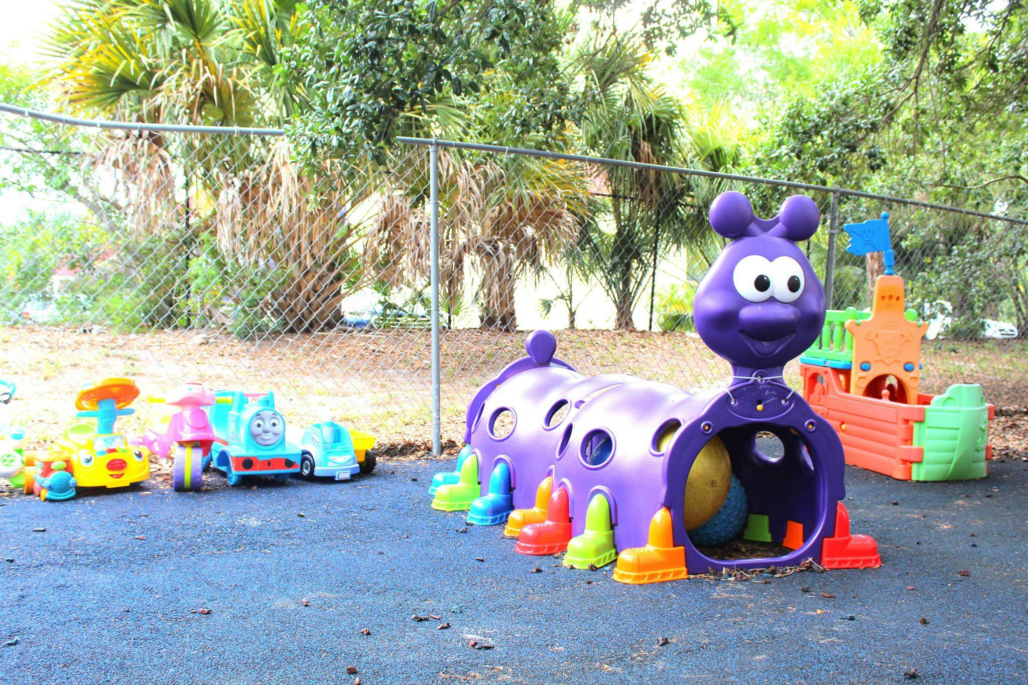 Playground with a purple caterpillar tunnel and other colorful toys