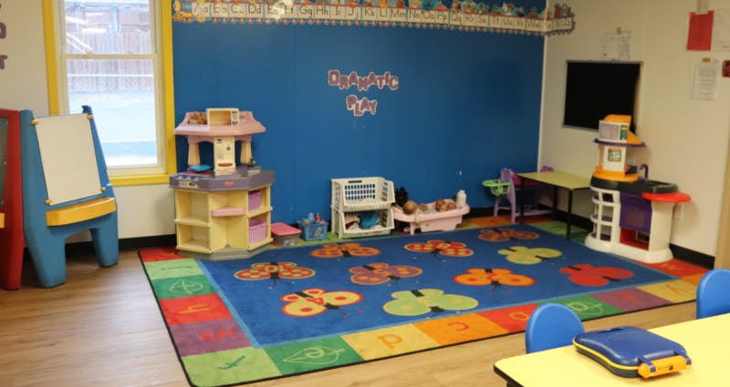 Playroom with blue walls, colorful rug, and various toys