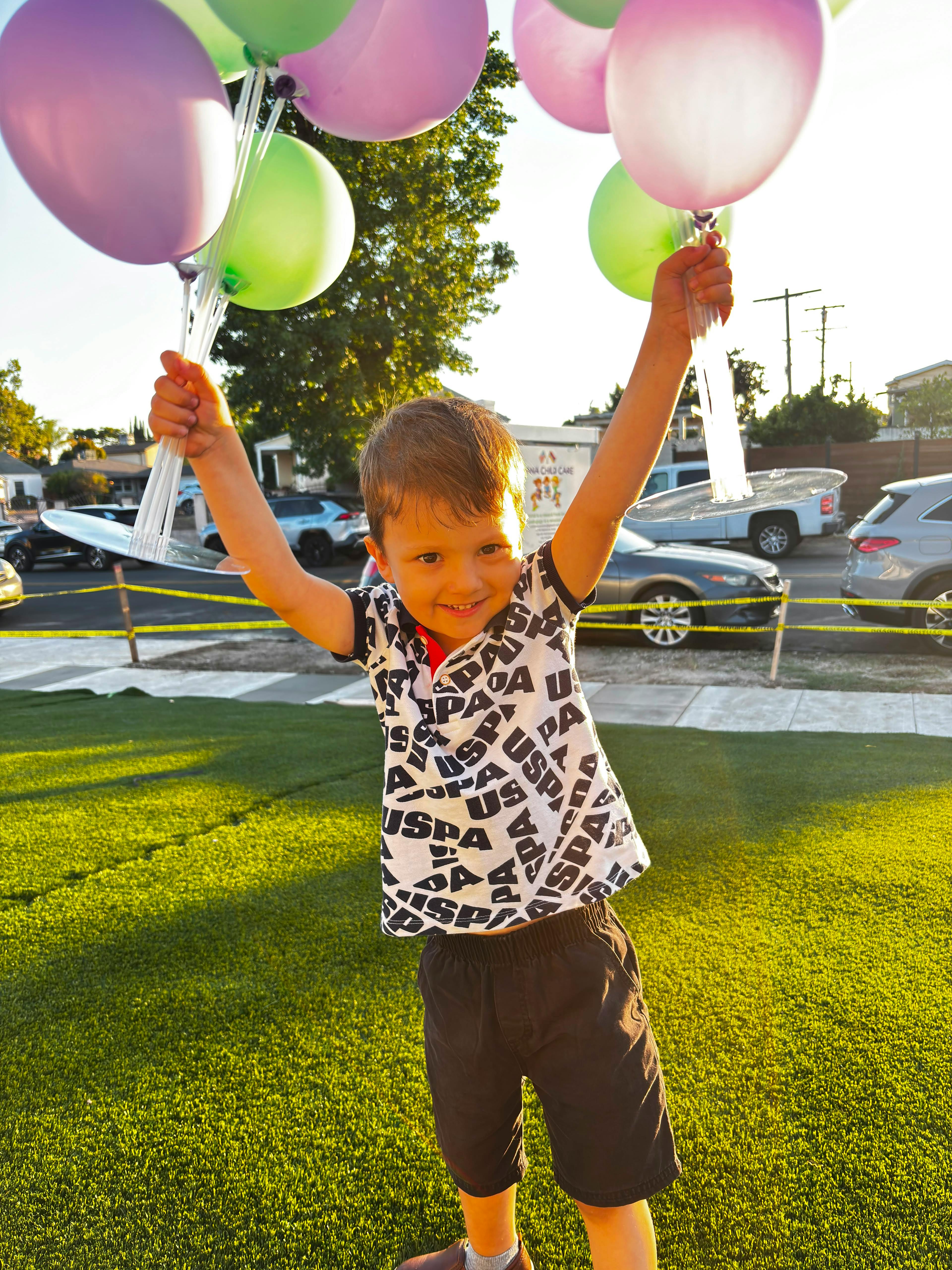 Child smiling while holding up a bunch of balloons