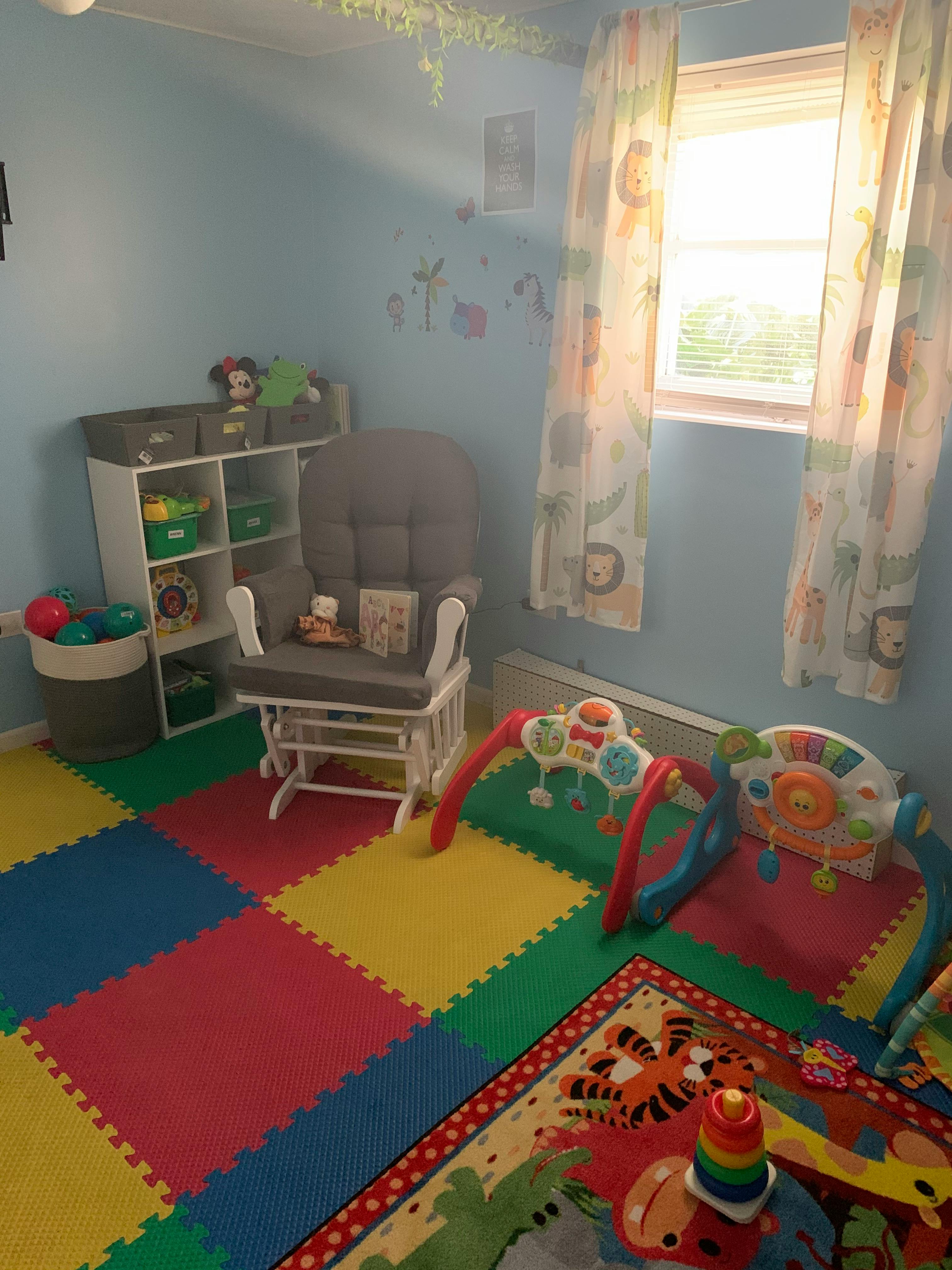 Nursery room with a rocking chair, toy shelf, and play mat