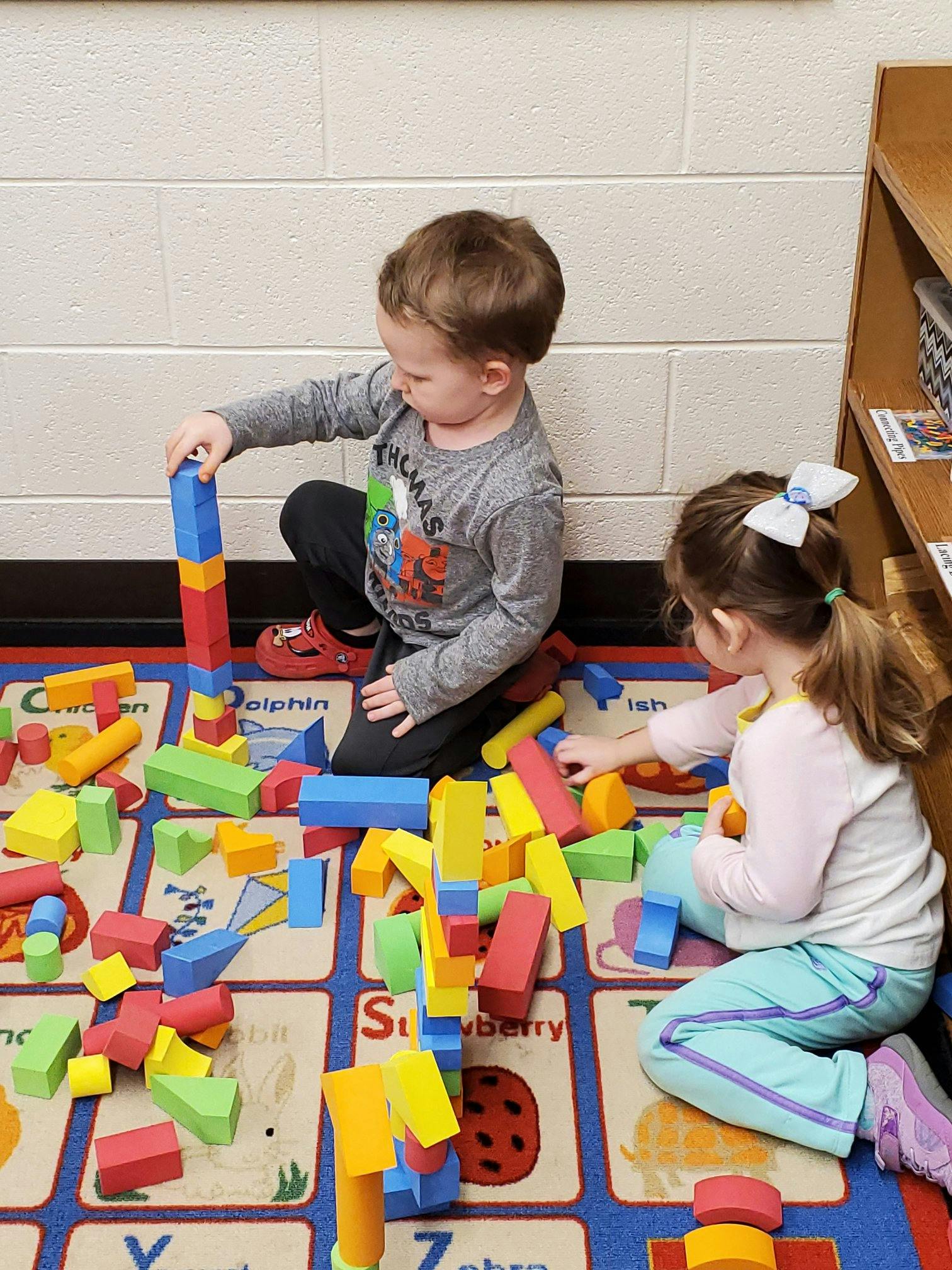 Two children playing with colorful building blocks on a rug