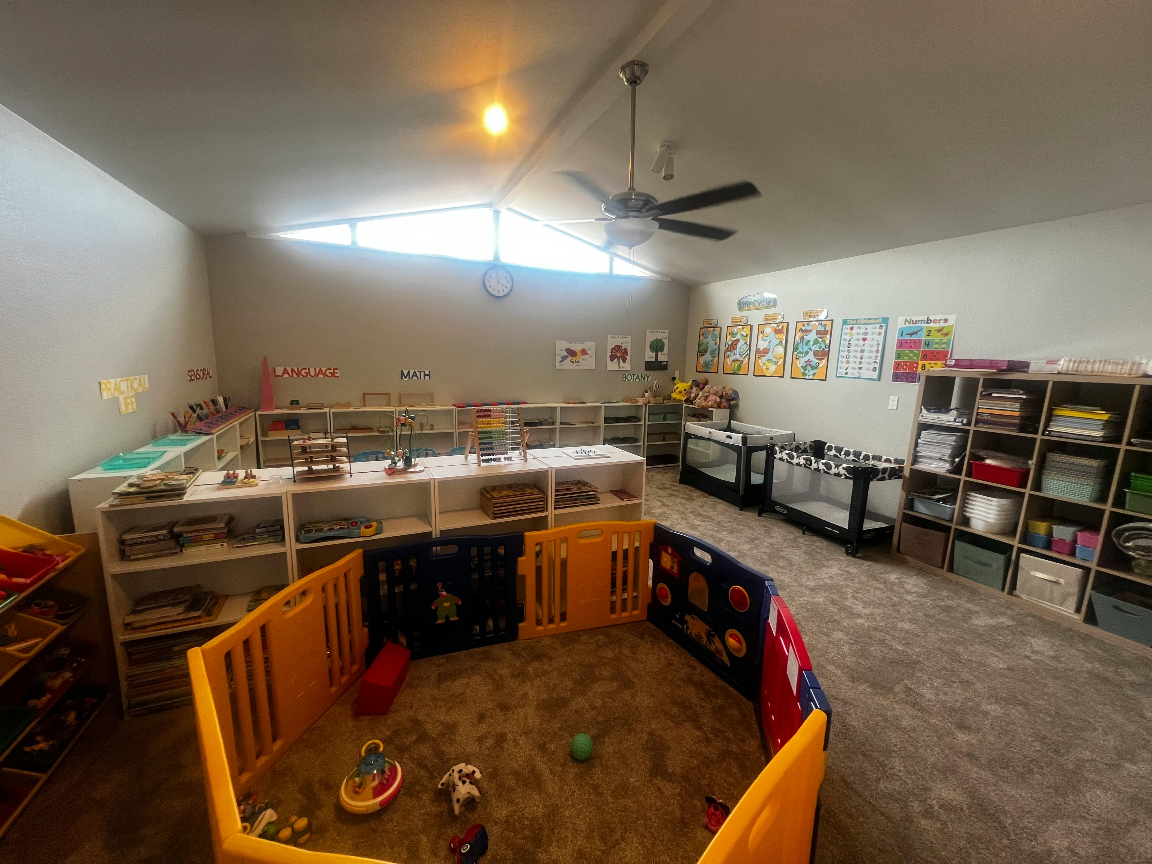 Playroom with a playpen, shelves, and cribs