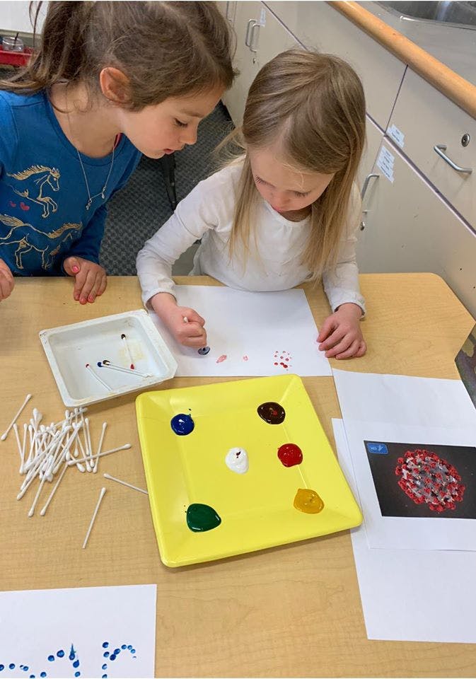 Two children painting with cotton swabs and colorful paints