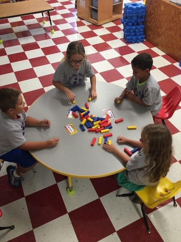Four children playing with colorful blocks at a round table