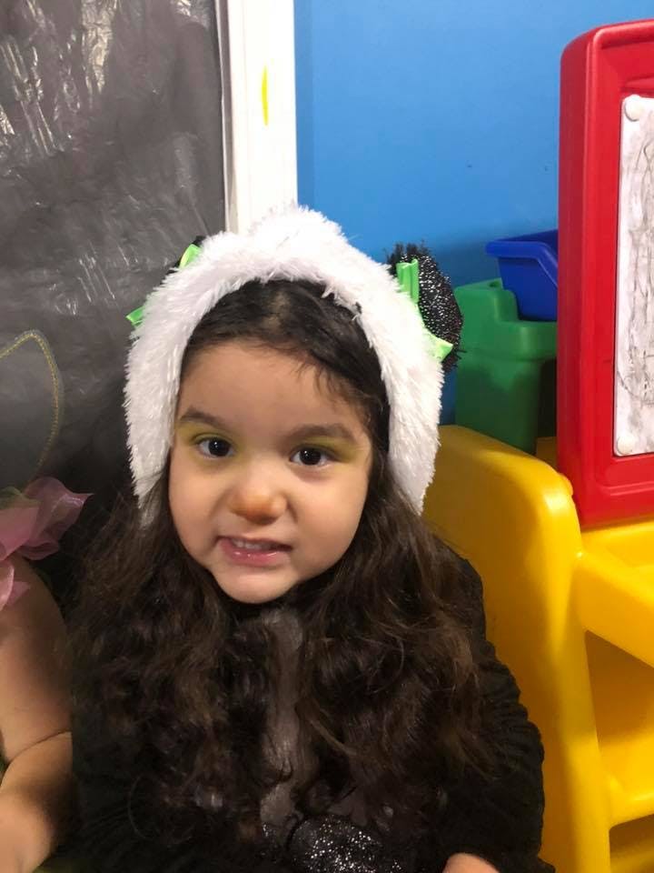 Child with long hair wearing a white furry headband