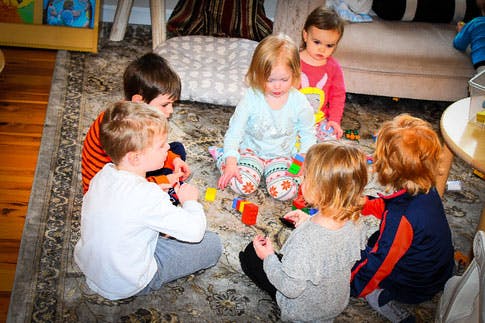 Group of children sitting on a rug playing with toys