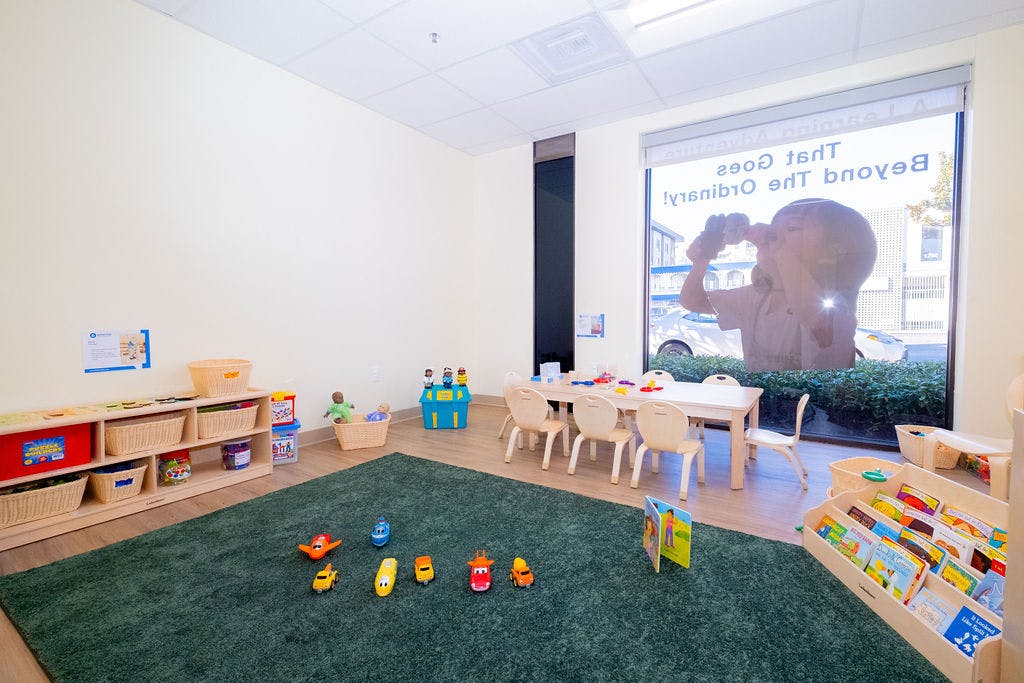 Classroom with child-sized furniture, toys, book display, and a rug