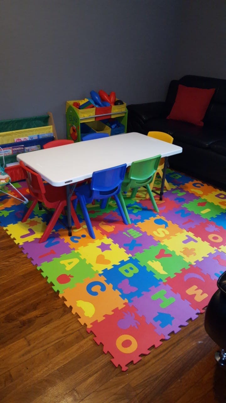 Children's play area with a table, chairs, and alphabet mat