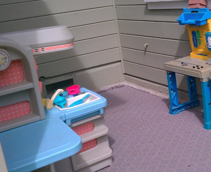 Two toy play sets, one with a sink and the other a workbench