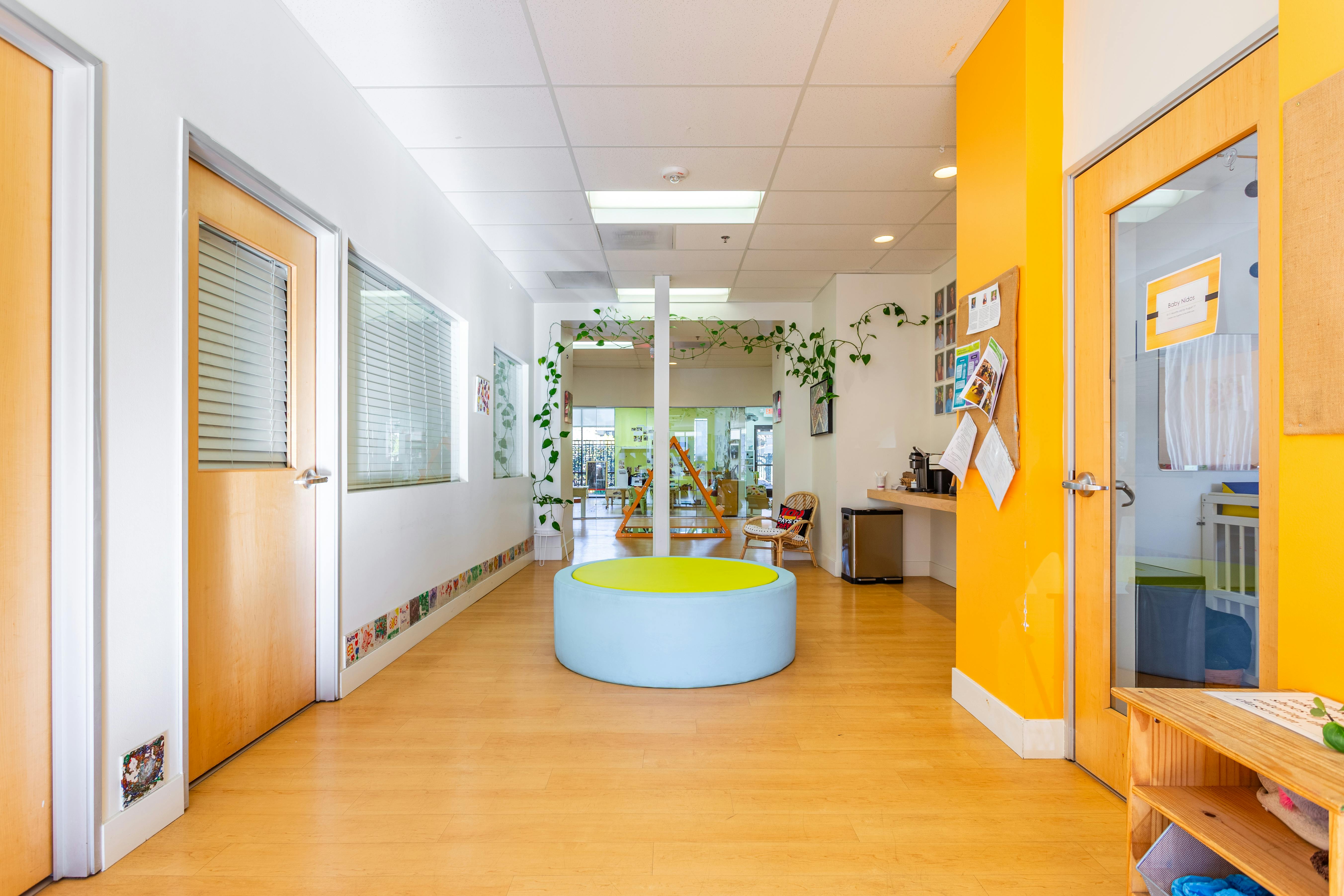 Hallway with light wood floors and a round blue and yellow playpen