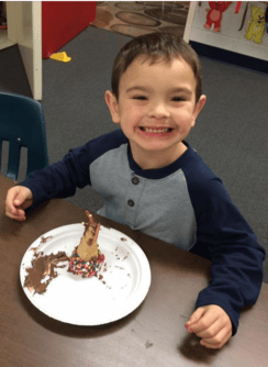 Child smiling at a table with a plate of dessert