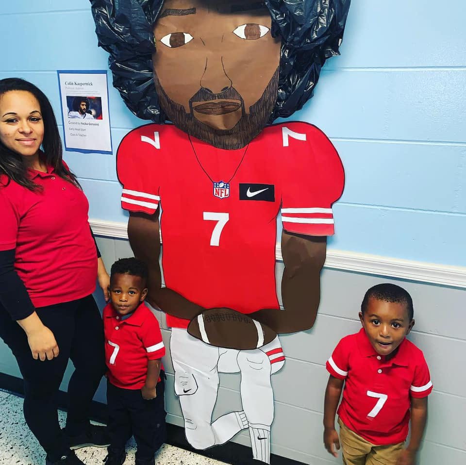Person and two children standing next to a large cutout of a football player