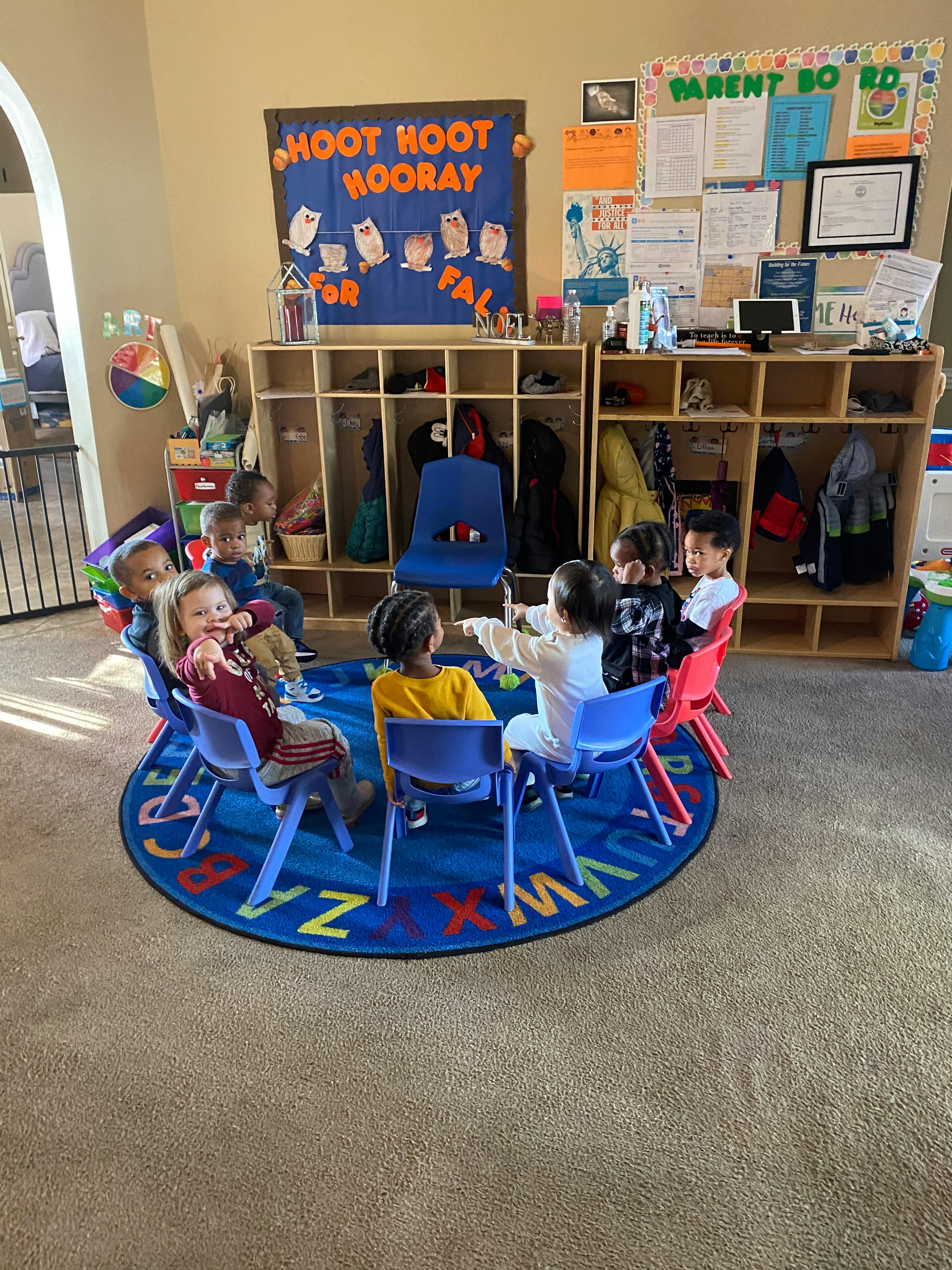 Children sitting in chairs on a rug in a classroom