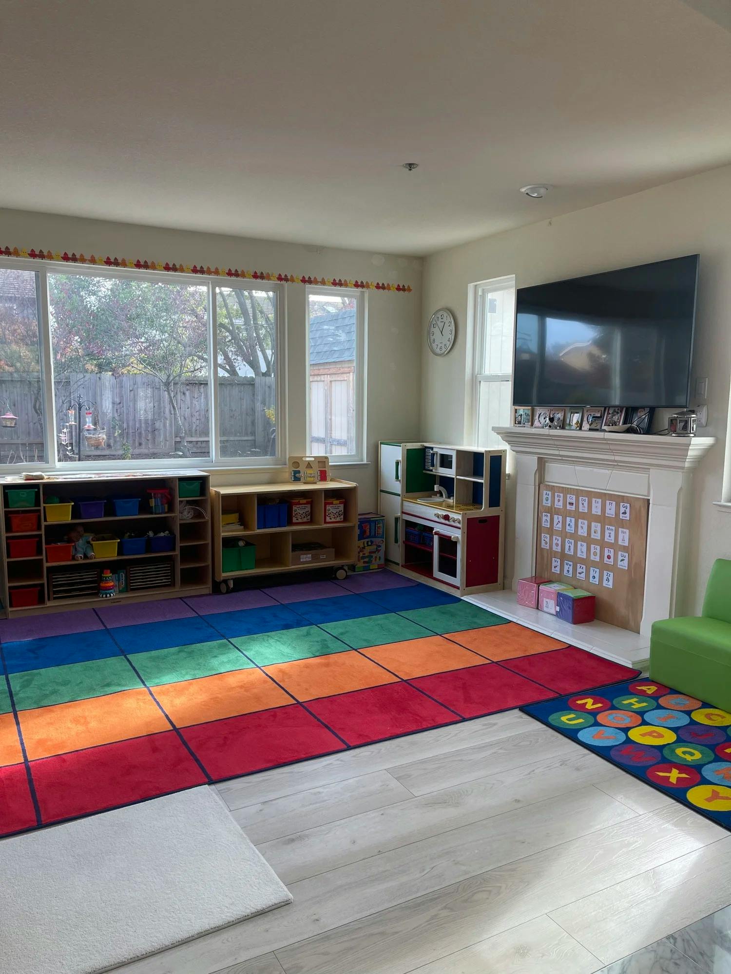 Colorful playroom with toy storage shelves, a play kitchen, and rugs