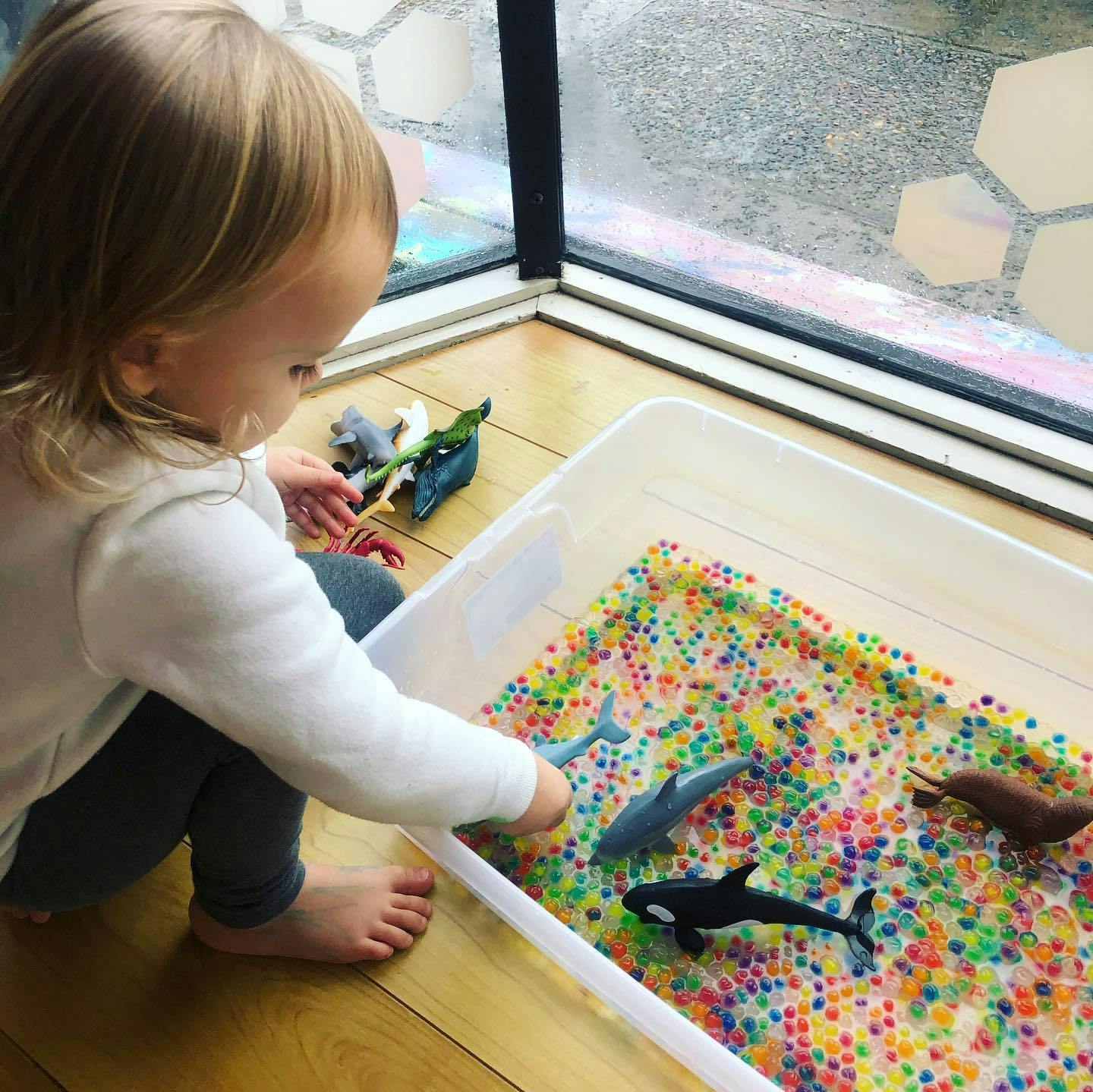 Child playing with water beads and toy sea animals in a bin