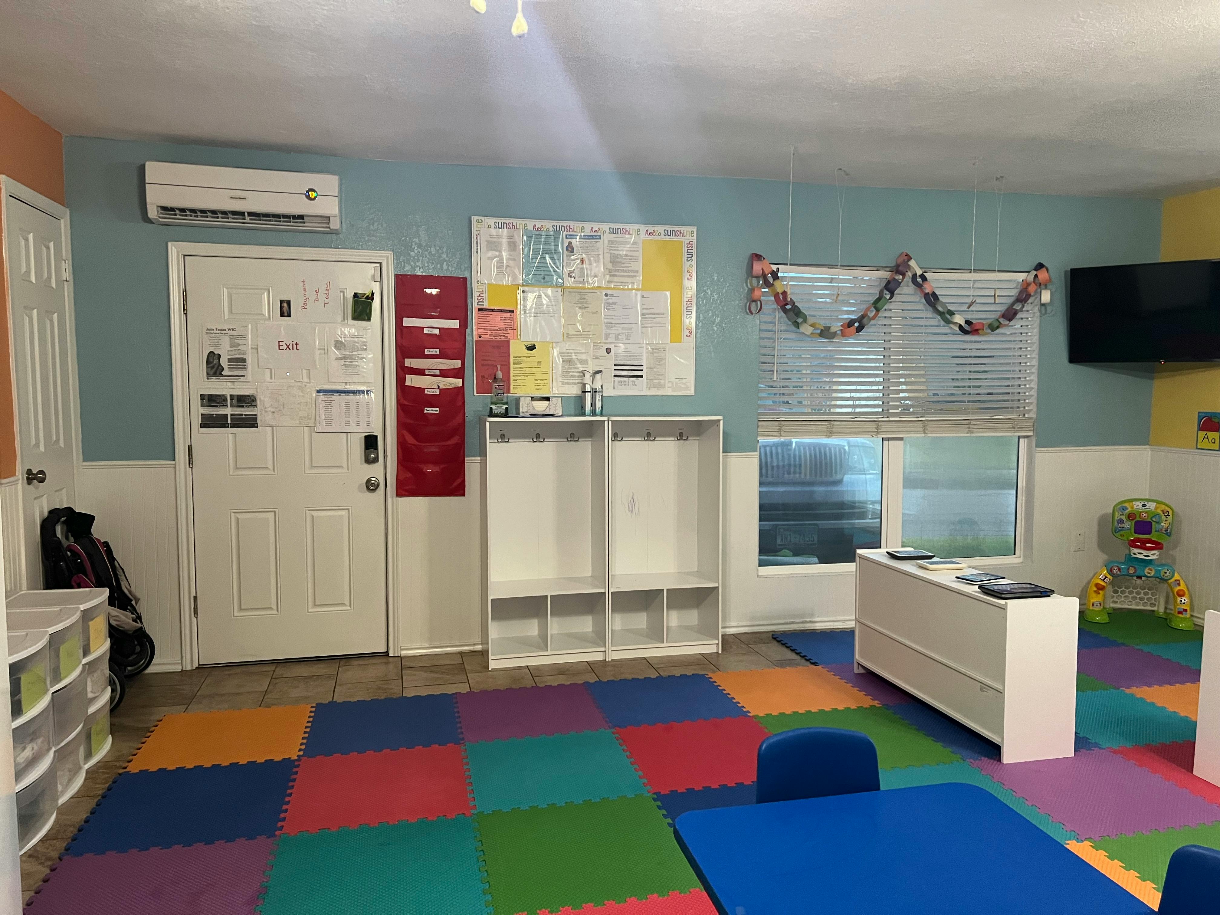 Classroom with colorful floor mats, white storage units, and a blue table
