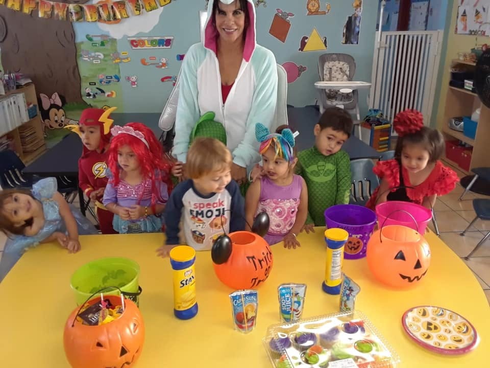 Adult and children in costumes around a table with Halloween decorations